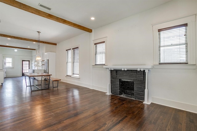 unfurnished living room featuring visible vents, beamed ceiling, baseboards, a fireplace, and wood finished floors