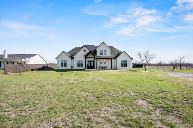 modern farmhouse style home with a front lawn, fence, and board and batten siding
