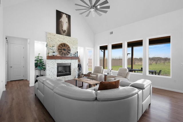 living room featuring high vaulted ceiling, baseboards, dark wood finished floors, visible vents, and a fireplace