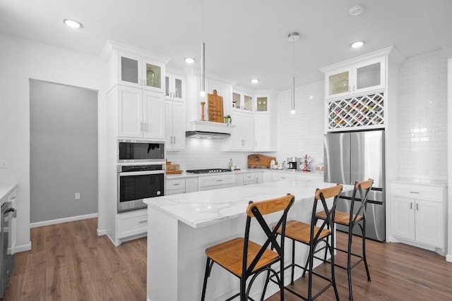 kitchen featuring white cabinetry, wood finished floors, backsplash, and stainless steel appliances