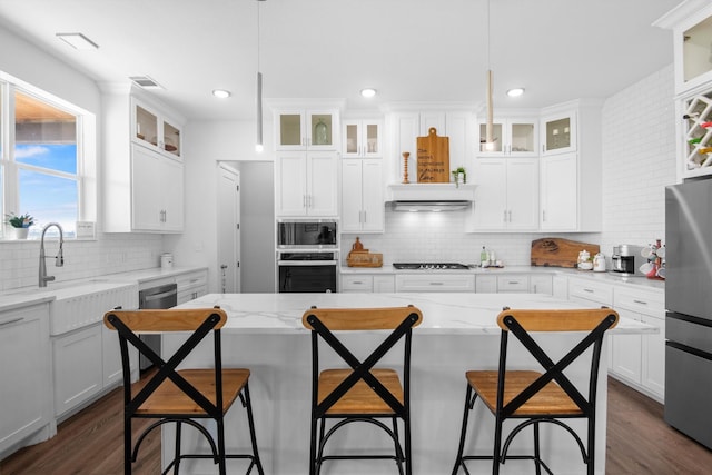 kitchen with dark wood finished floors, stainless steel appliances, a breakfast bar, and visible vents