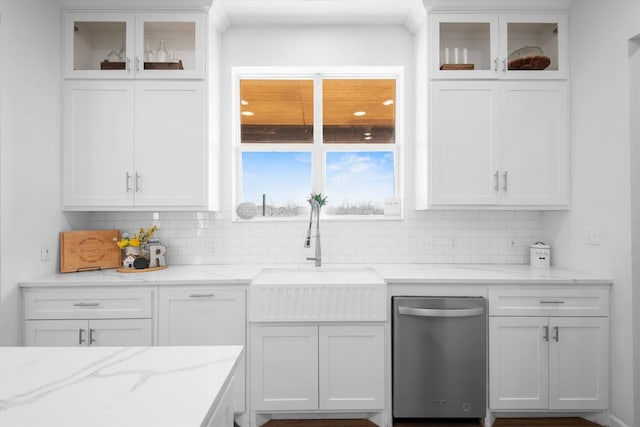 kitchen featuring decorative backsplash, glass insert cabinets, white cabinetry, a sink, and light stone counters