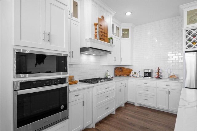 kitchen with dark wood finished floors, white cabinetry, backsplash, and appliances with stainless steel finishes