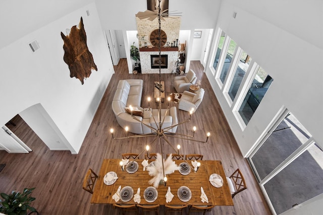living area with arched walkways, high vaulted ceiling, wood finished floors, and a fireplace