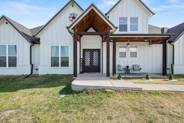 modern inspired farmhouse featuring roof with shingles, french doors, board and batten siding, a front yard, and a porch