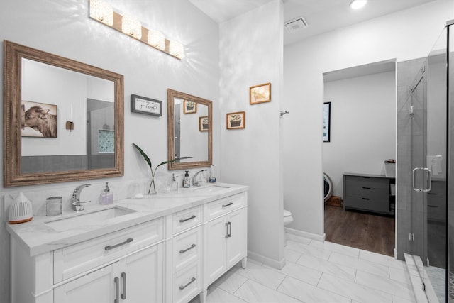 bathroom with a stall shower, double vanity, visible vents, and a sink