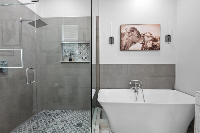 bathroom featuring a freestanding bath, tile walls, and a shower stall