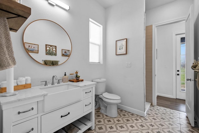 bathroom featuring tile patterned floors, toilet, vanity, walk in shower, and baseboards