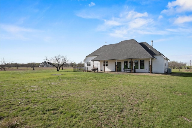 back of property featuring a lawn, central AC, roof with shingles, and a patio area