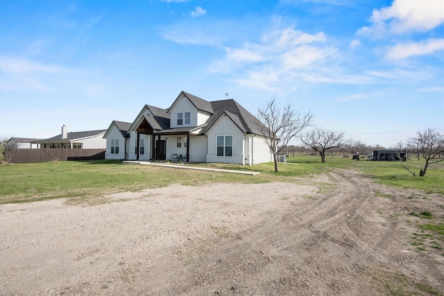 modern farmhouse style home featuring a front yard, fence, and board and batten siding