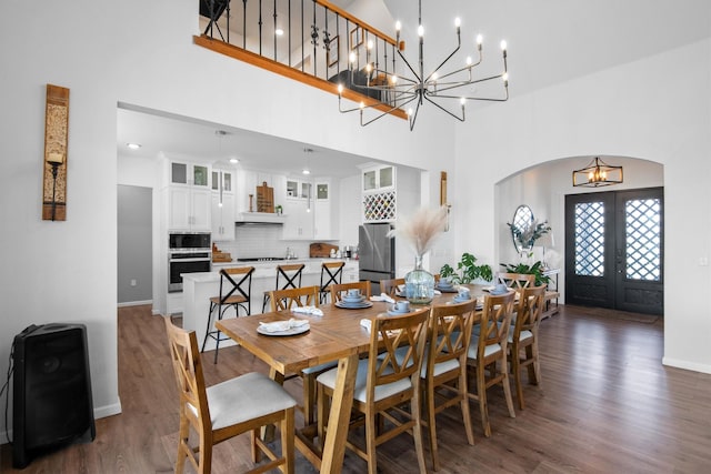 dining room with arched walkways, wood finished floors, french doors, and a chandelier