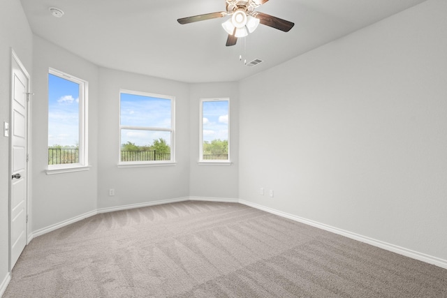 carpeted spare room featuring baseboards, ceiling fan, and visible vents