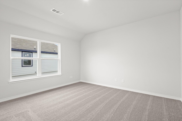 carpeted empty room featuring baseboards, lofted ceiling, and visible vents