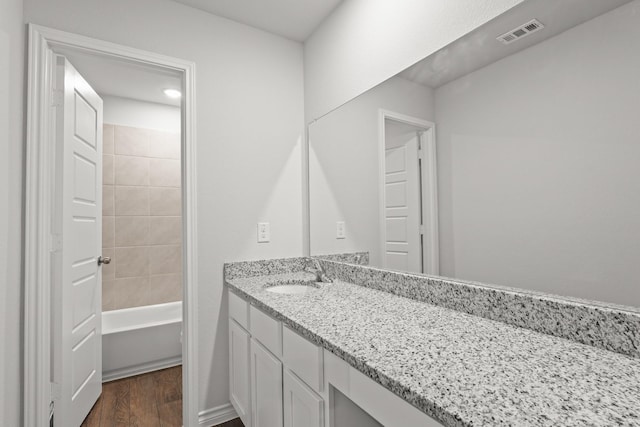 bathroom featuring visible vents, wood finished floors, shower / bathing tub combination, and vanity