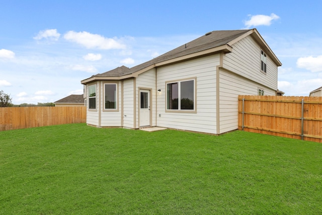back of property featuring a lawn, a fenced backyard, and roof with shingles