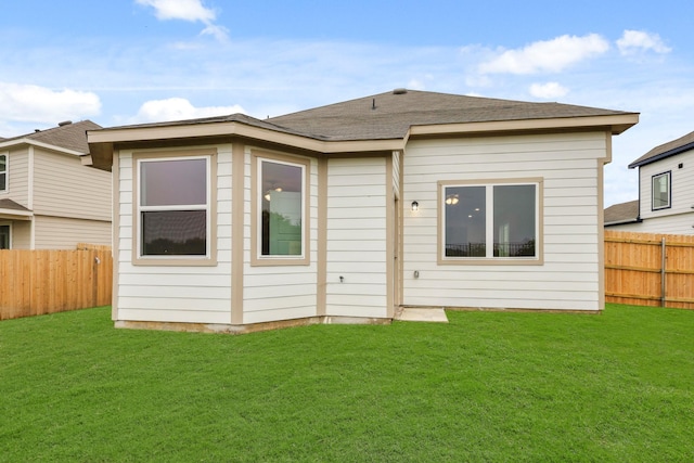 rear view of property with a fenced backyard, roof with shingles, and a lawn
