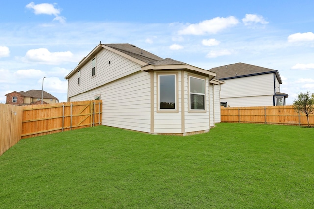 back of house featuring a fenced backyard and a lawn