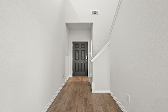 hall with dark wood-style flooring, baseboards, and visible vents