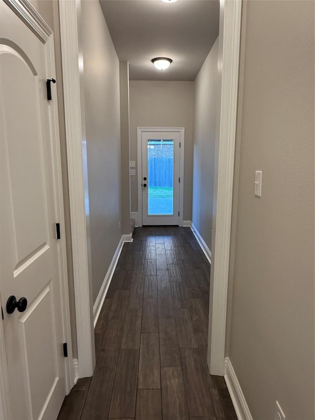 doorway with dark wood-type flooring and baseboards