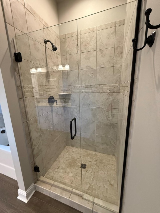 full bathroom with a shower stall, baseboards, and wood finished floors