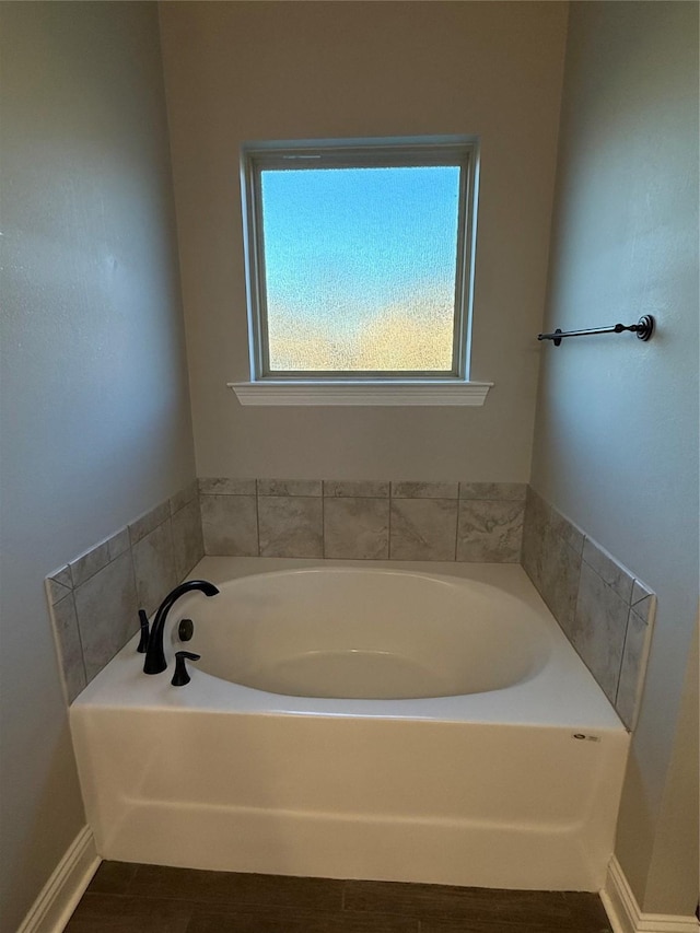 bathroom with a bath and baseboards