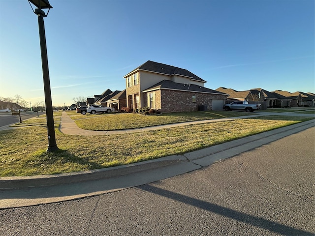 view of front of home with a residential view, a front lawn, driveway, brick siding, and an attached garage