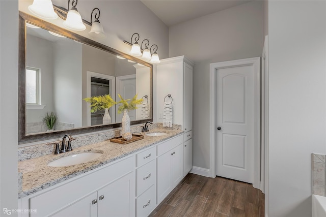 918 Hackberry Dr, Bossier City, LA 71111 - bathroom featuring double vanity, wood finished floors, baseboards, and a tub to relax in