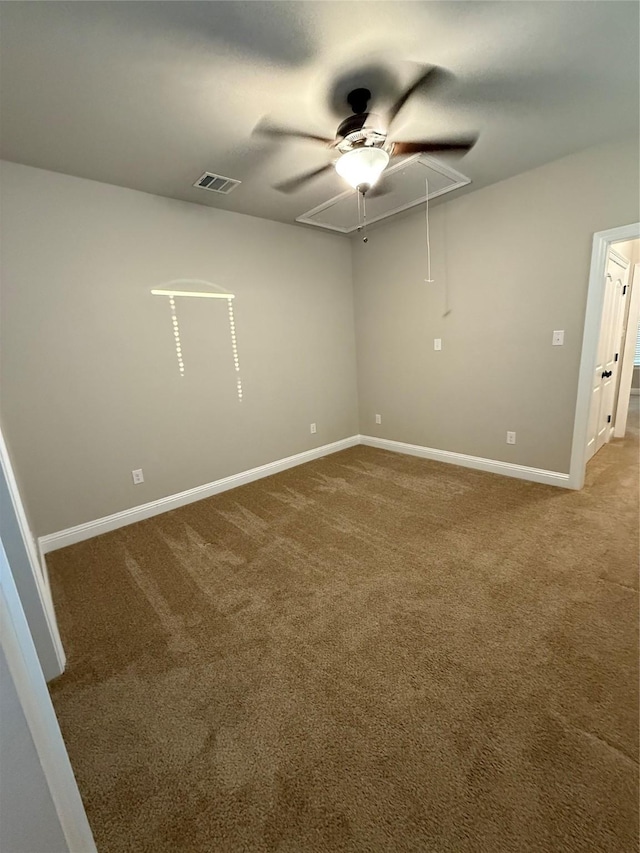 carpeted spare room featuring attic access, baseboards, visible vents, and ceiling fan