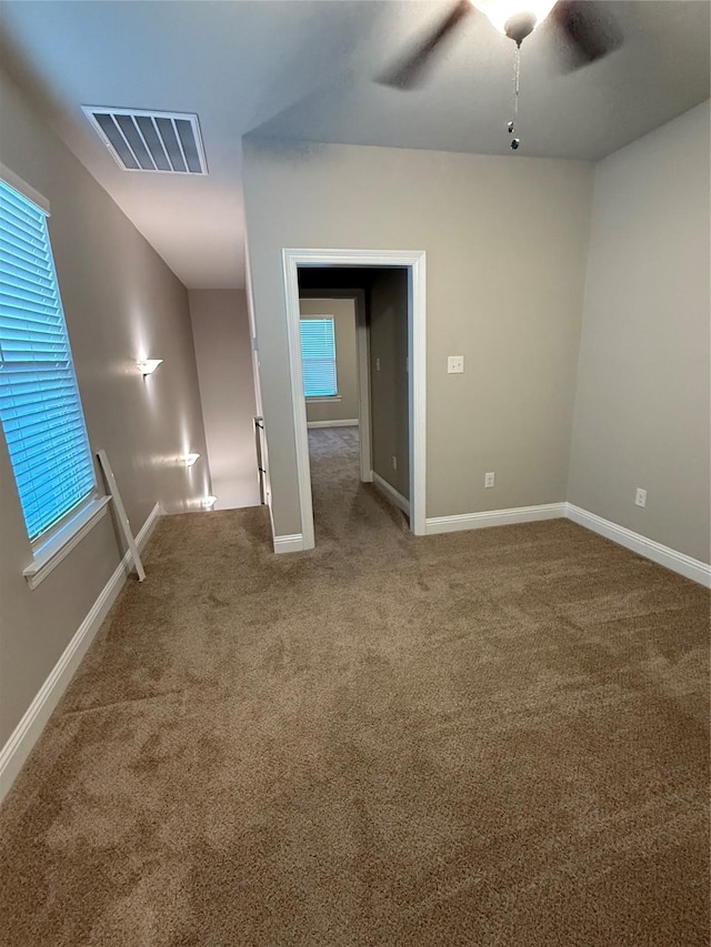 carpeted spare room with visible vents, a ceiling fan, and baseboards