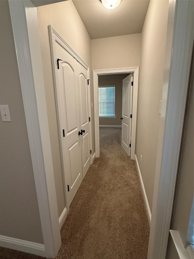 hallway with carpet floors and baseboards