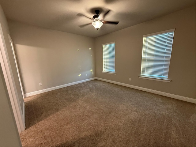 unfurnished room with carpet floors, a ceiling fan, and baseboards