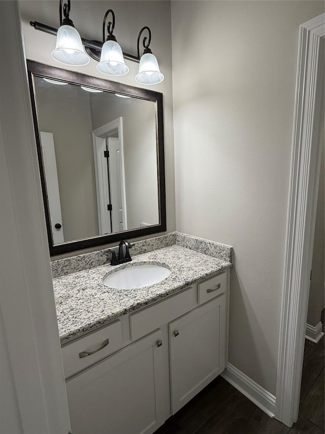 bathroom with baseboards, vanity, and wood finished floors