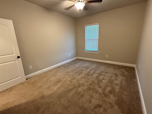 carpeted spare room featuring baseboards and a ceiling fan