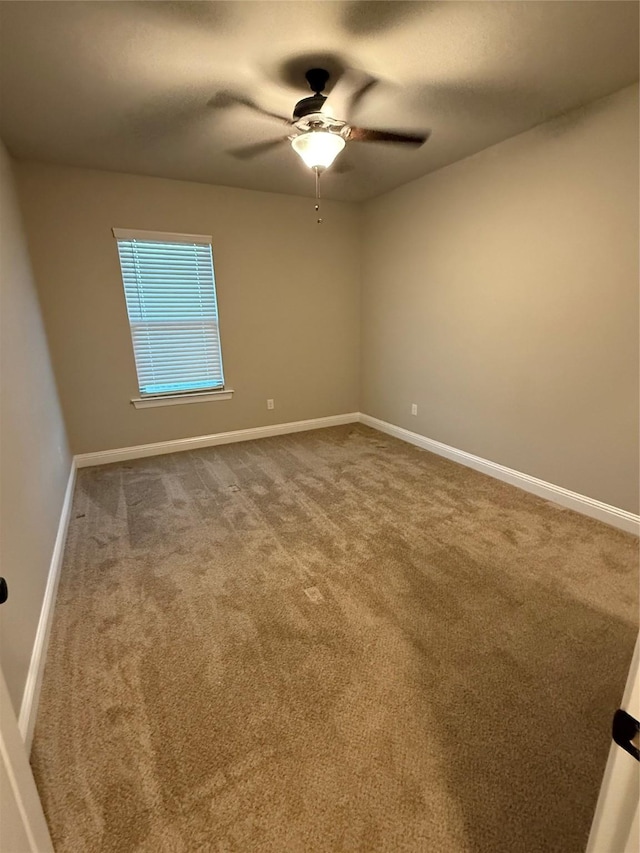spare room featuring carpet floors, a ceiling fan, and baseboards