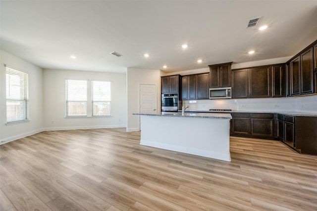 406 Eaton Dr, Justin, TX 76247 - kitchen featuring a kitchen island with sink, a sink, stainless steel microwave, light wood-type flooring, and visible vents