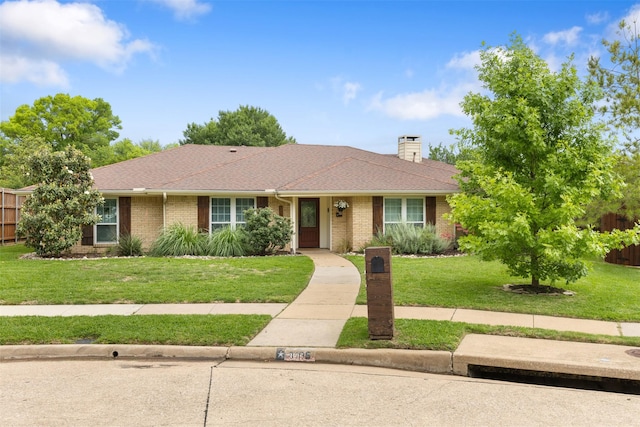 ranch-style house featuring brick siding, a chimney, and a front yard