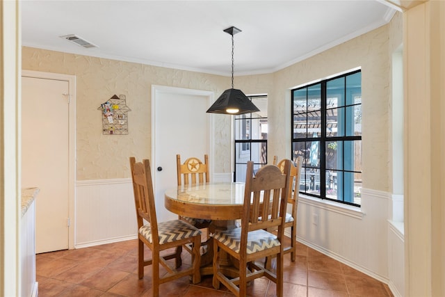 dining space with light tile patterned flooring, visible vents, wainscoting, and a wealth of natural light