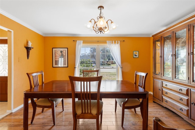 dining area featuring baseboards, a chandelier, ornamental molding, and light wood finished floors