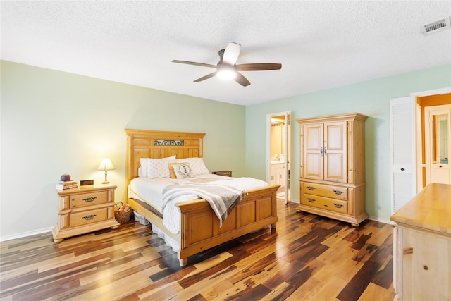 bedroom featuring visible vents, a textured ceiling, ensuite bath, and wood finished floors