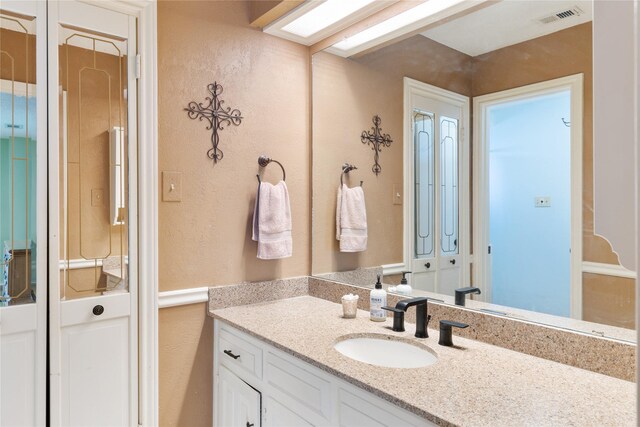 bathroom featuring a textured wall, visible vents, and vanity