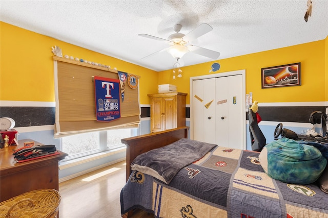 bedroom with a textured ceiling, ceiling fan, baseboards, and a closet