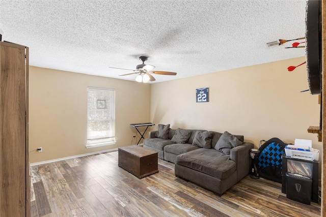 living room with baseboards, ceiling fan, dark wood-style flooring, and a textured ceiling