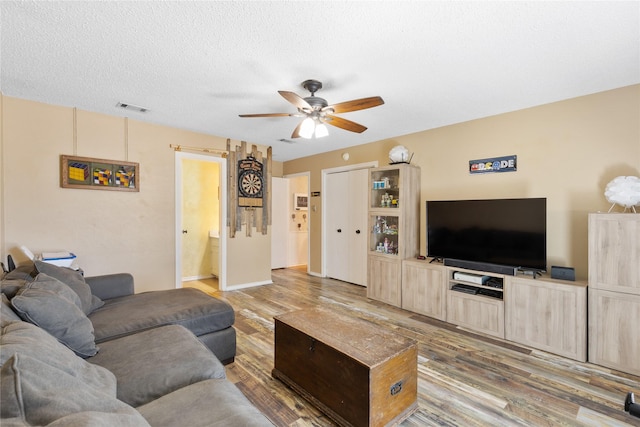 living room with visible vents, a ceiling fan, and wood finished floors