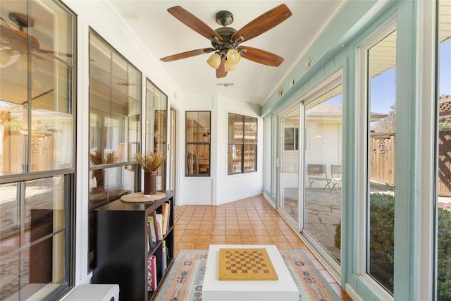 sunroom / solarium with tile patterned flooring and ceiling fan