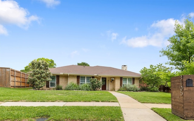 single story home featuring fence, a chimney, brick siding, and a front yard