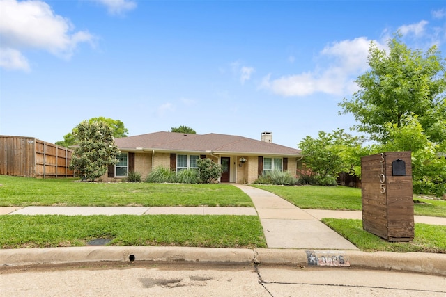 ranch-style house featuring brick siding, fence, a chimney, and a front lawn