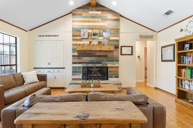 living room with light wood finished floors, wood walls, vaulted ceiling, visible vents, and ornamental molding