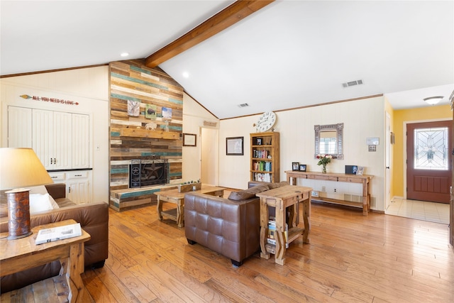 living area with visible vents, vaulted ceiling with beams, light wood finished floors, and a fireplace