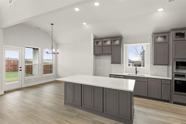 kitchen featuring vaulted ceiling, gray cabinets, a sink, decorative backsplash, and oven