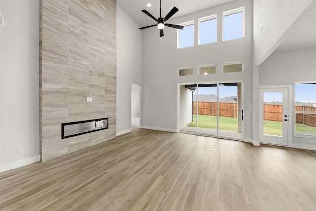 unfurnished living room featuring a ceiling fan, baseboards, a fireplace, and wood finished floors